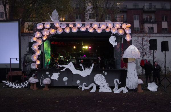A pop-up proscenium theatre decorated with lit up white paper decor.