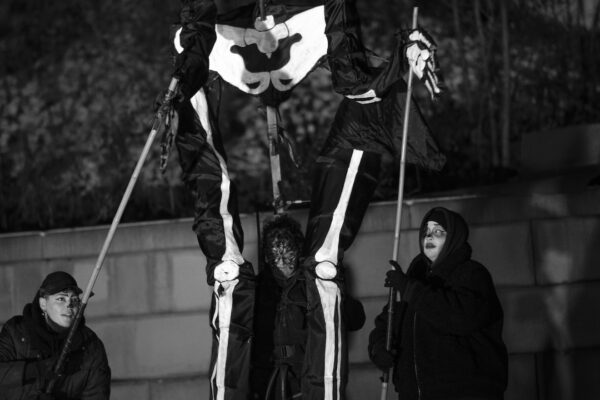 Three puppeteers, dressed in black, puppetting, from the ground, a 20 foot tall skeleton puppet.