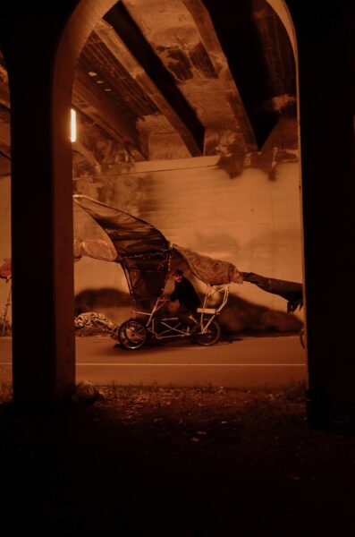 A crow bike puppet sits under the 10th Ave bridge before being ridden onto the stage. Puppet by Peter Schulze and Xena Huff. Extravaganza 2022. Photo by Lucy Moroukian. 