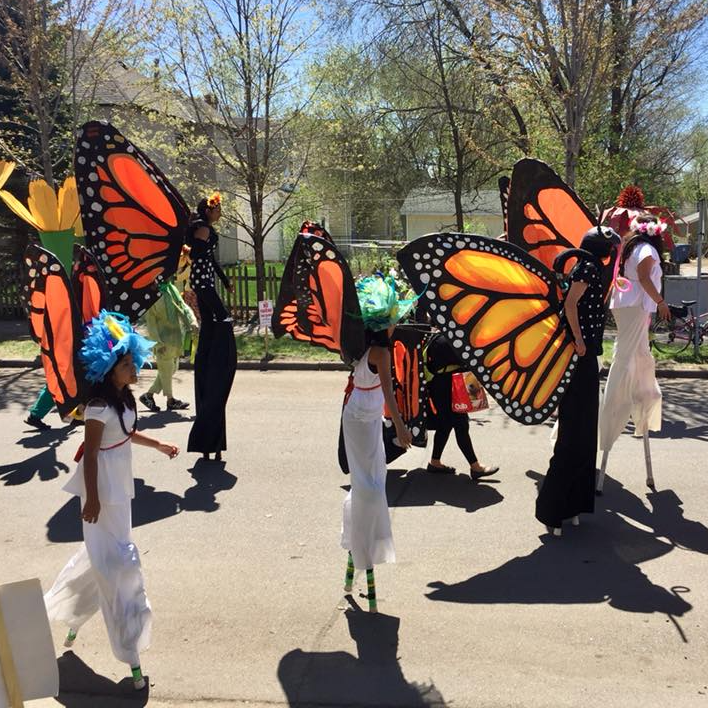 Stilters wearing monarch wings at the May Day parade.